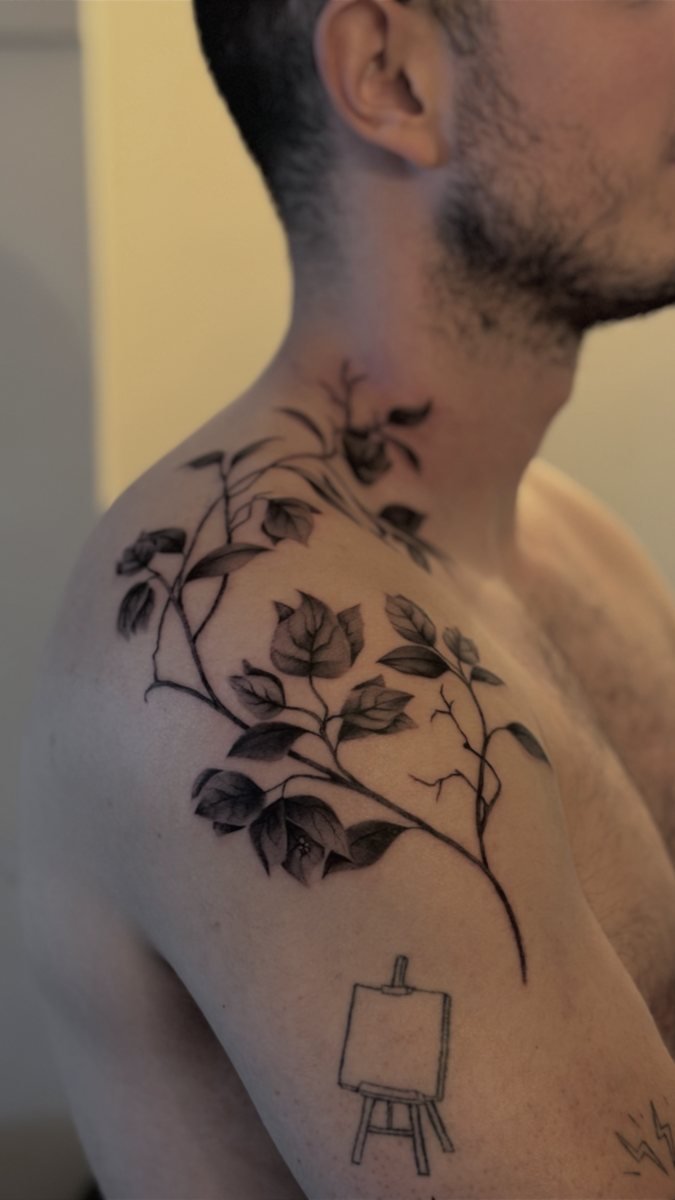 Tatuagem floral de galhos e folhas no ombro